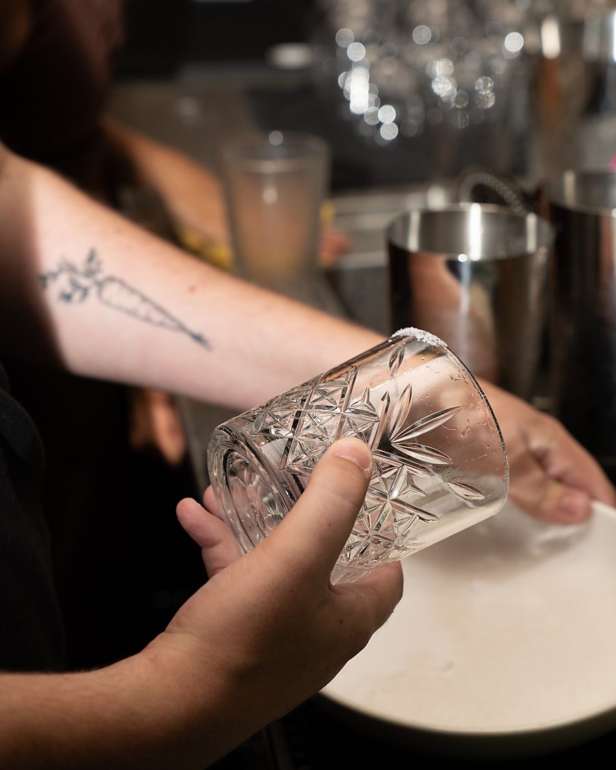 A bartender polishing a cut-crystal glass behind the bar
