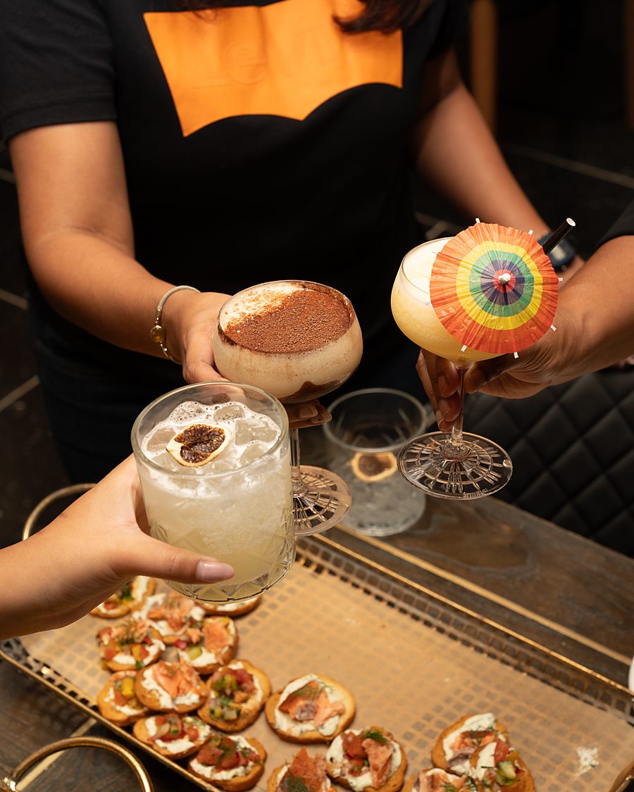 Two guests clinking cocktails over a tray of canapés