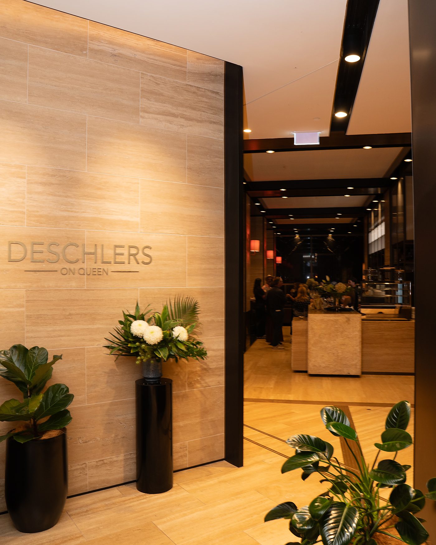 The Deschlers on Queen entrance, with the engraved travertine wall and fresh flowers, looking through to the bar