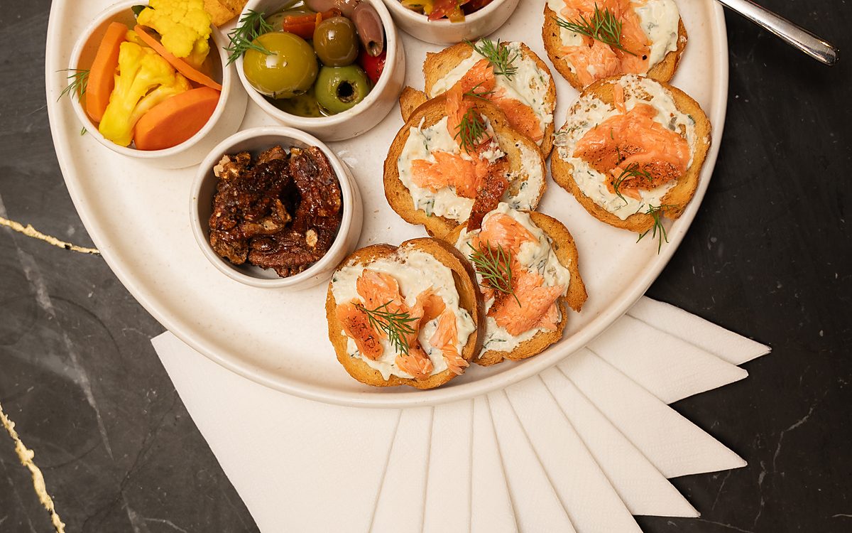 Smoked salmon crostini with pickles and olives on a platter
