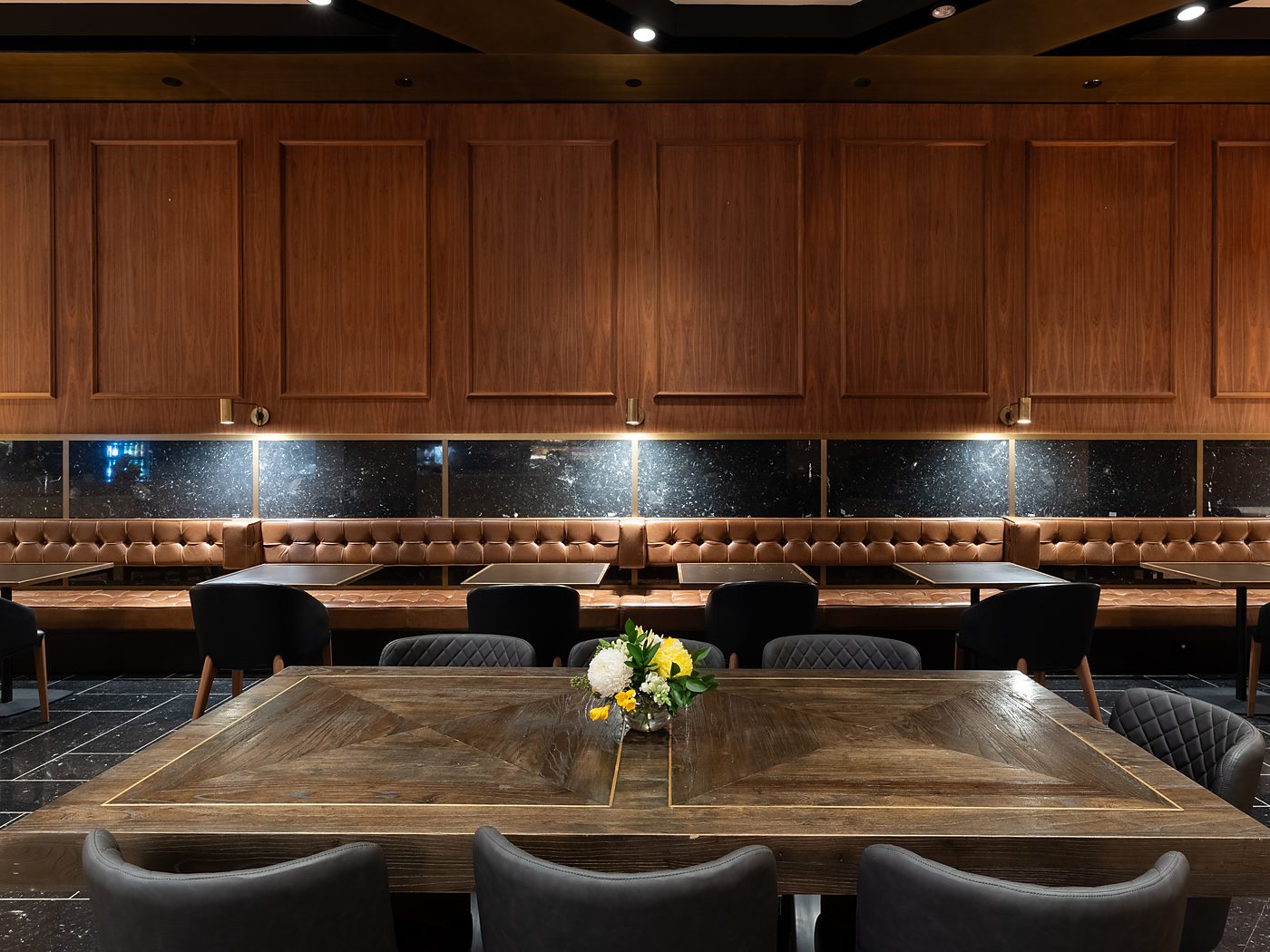 The long timber table set with flowers, leather banquettes behind