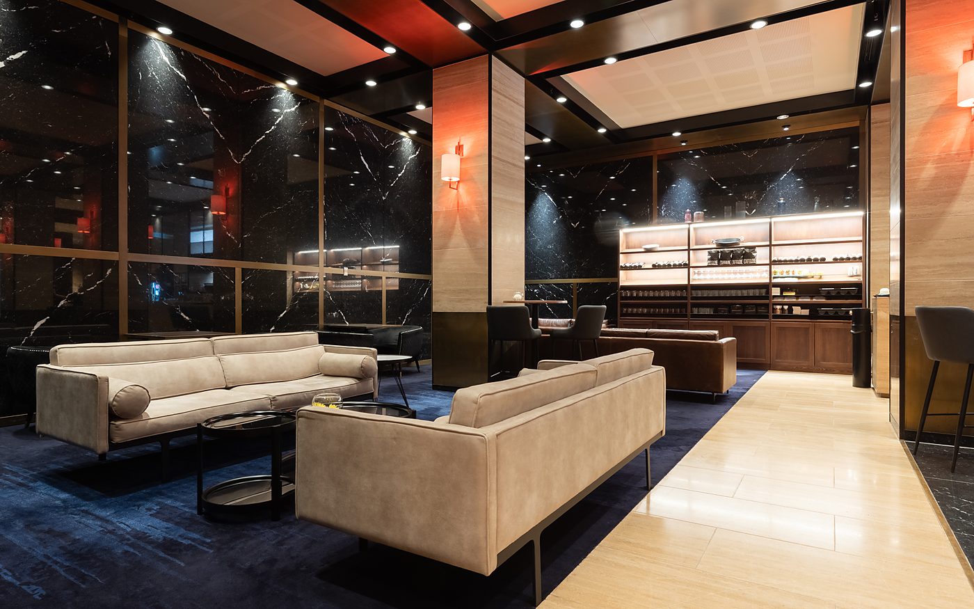 The lounge with cream sofas on a navy rug, pendant lights above