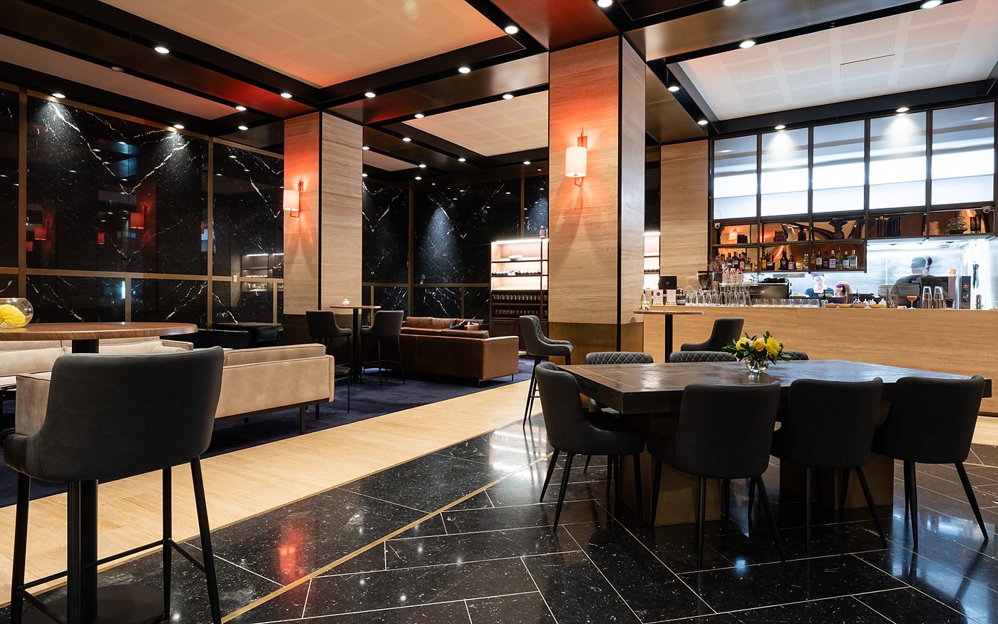 Dining tables and chairs across the marble floor, with the bar beyond